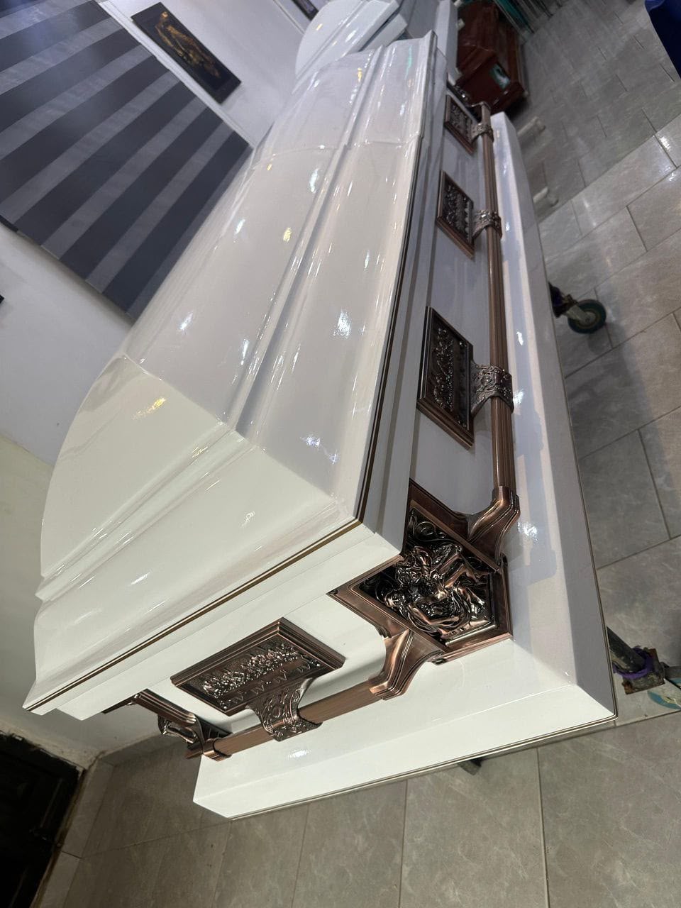 White casket with bronze-tone handles viewed from above