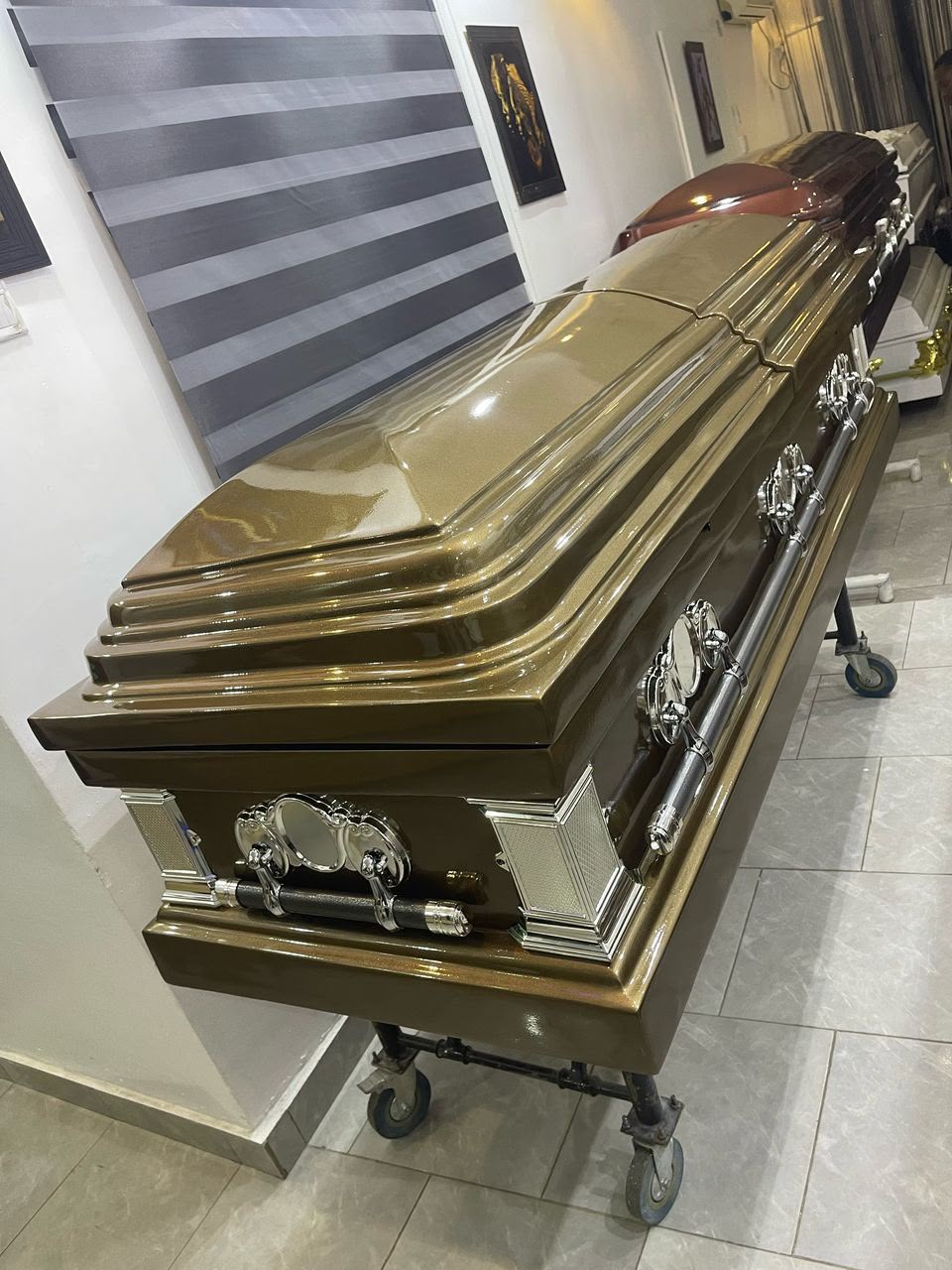 Olive-bronze casket with a sculpted lid and silver-tone handles