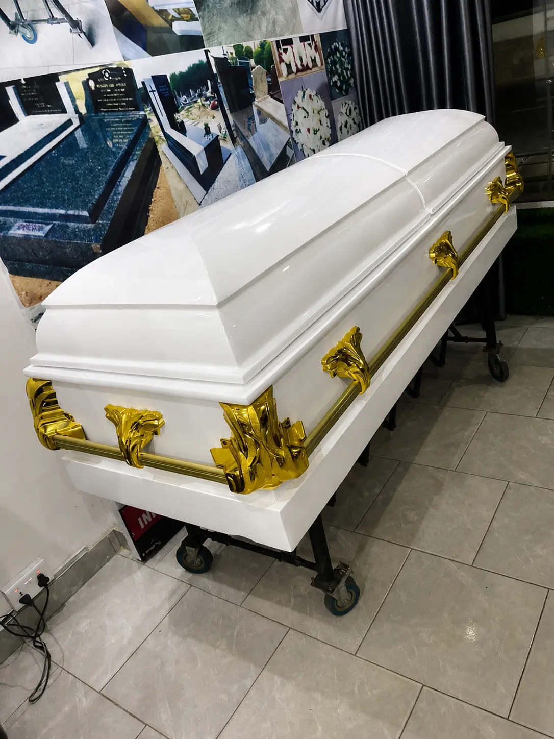 Royal white gloss casket with sculpted gold leaf handles displayed in a showroom