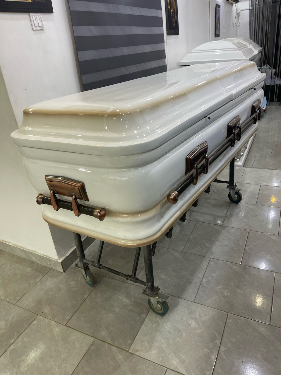 Pearl white casket with bronze-tone handles in the showroom