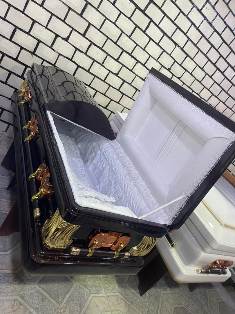 Half-couch black casket with a white ruched interior and gold corner fixtures