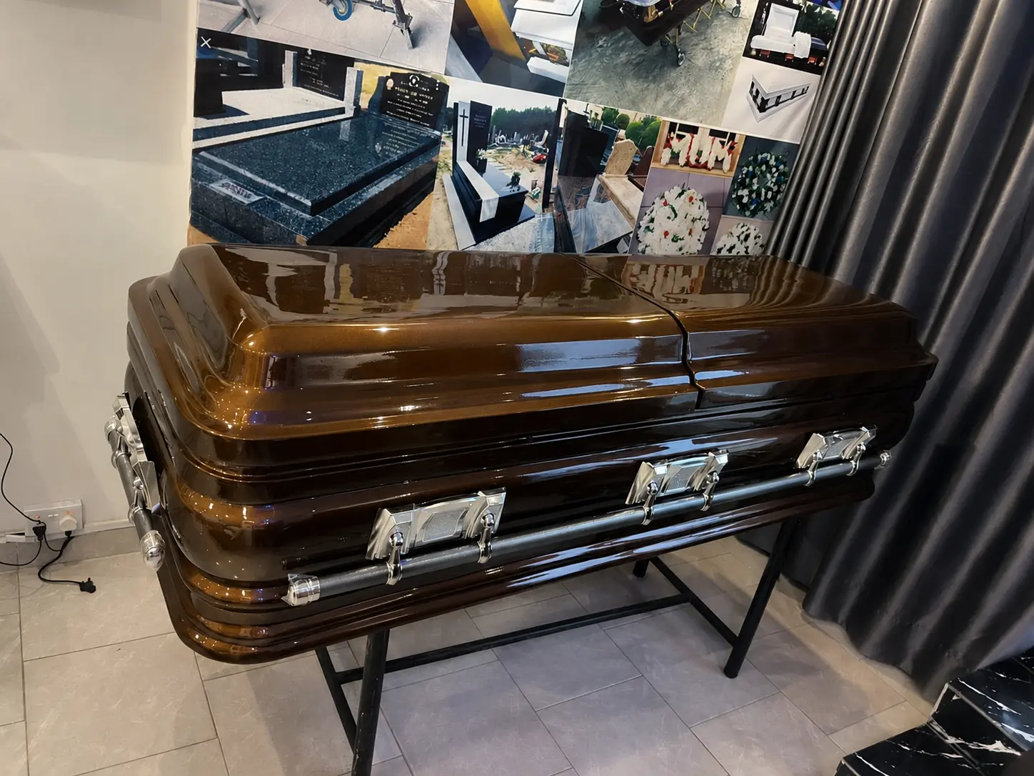 Amber brown metallic casket with brushed silver handles on a black stand