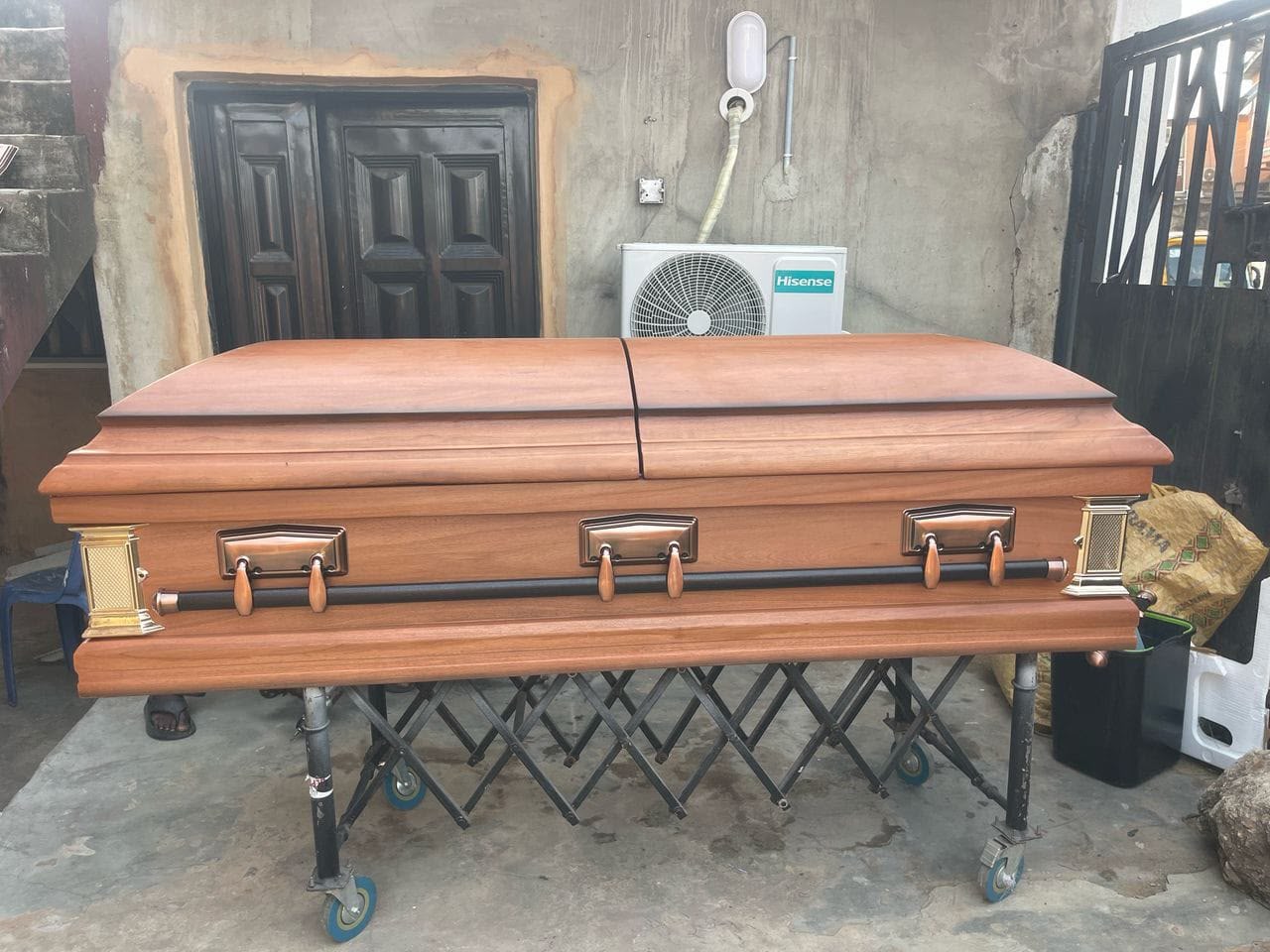 Copper-toned oak casket with bronze handles on a trolley