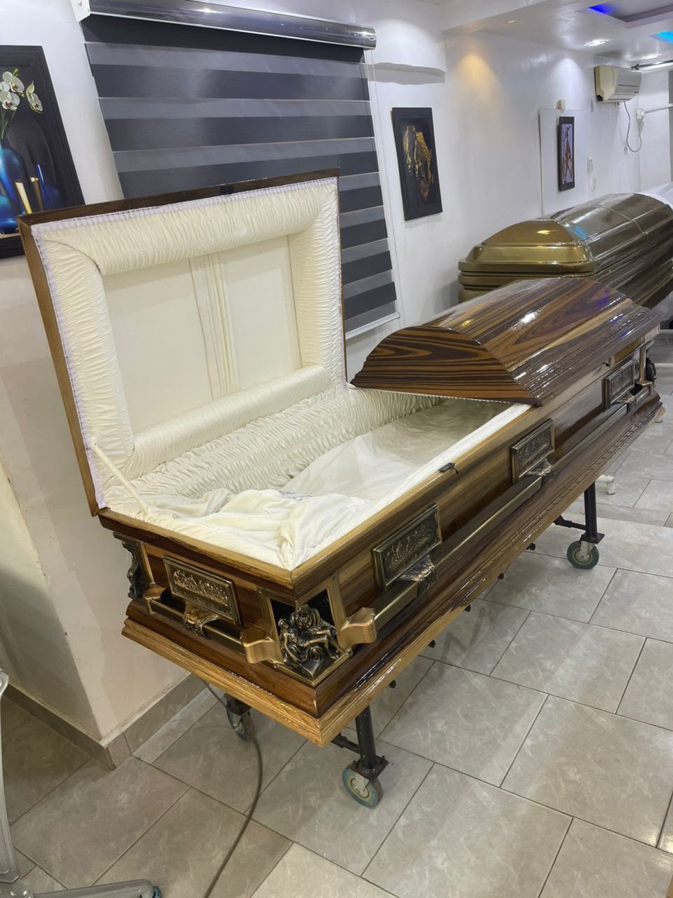 Open wood-finish casket showing its cream padded interior
