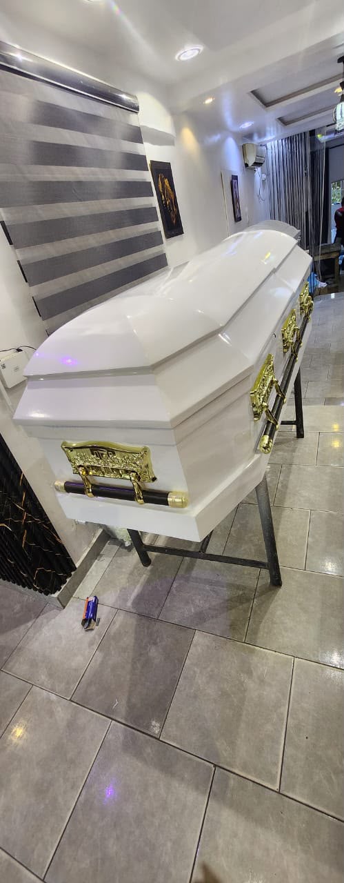 White casket with gold-tone fittings displayed in the showroom