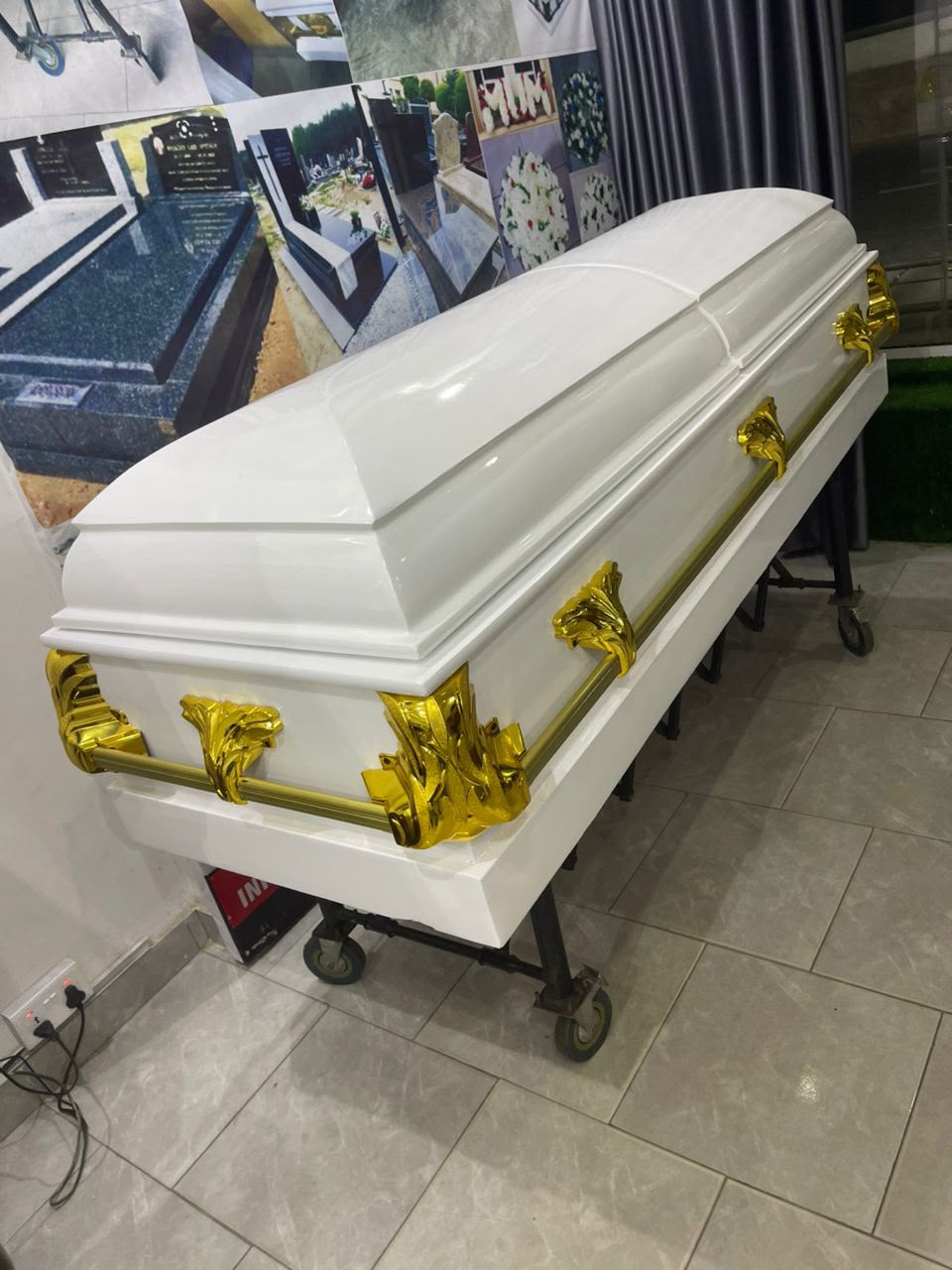 White casket with gold-tone corner ornaments and handles