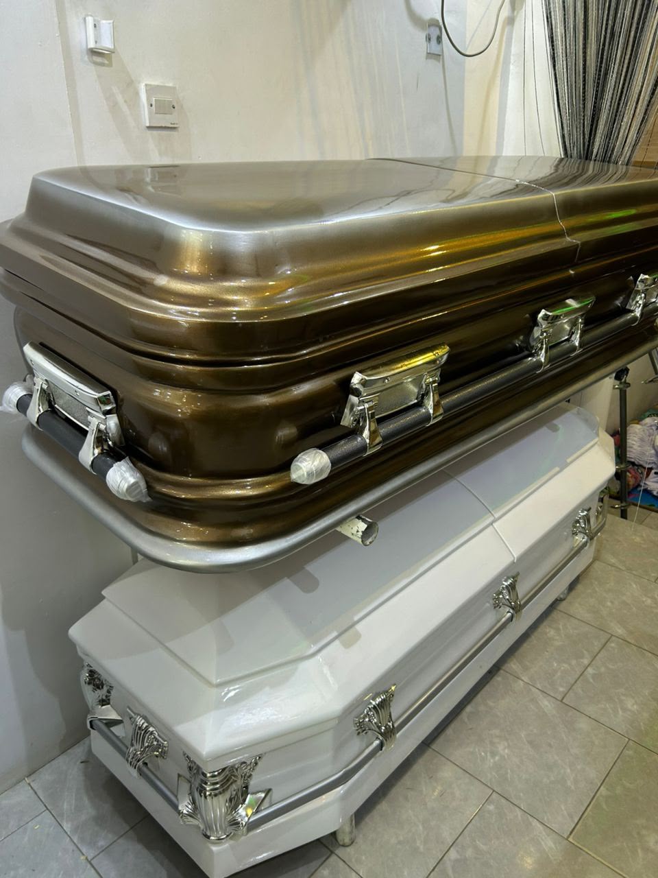 Bronze and white caskets stacked in the MJ Rosaries showroom